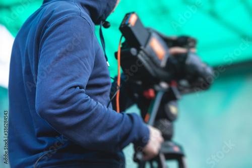 View of a camera man operator working during tv reportage, online broadcasting of concert, professional videographer with camera filming live event