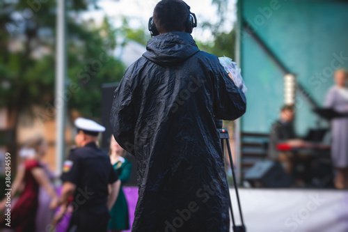 View of a camera man operator working during tv reportage, online broadcasting of concert, professional videographer with camera filming live event