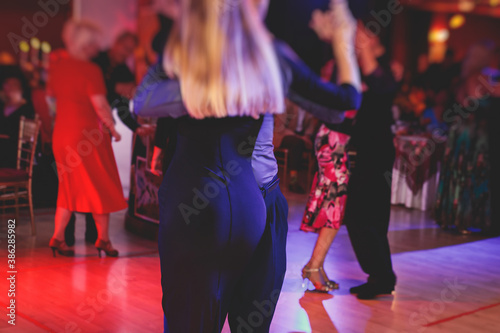 Couples dancing traditional latin argentinian dance milonga in the ballroom, tango salsa bachata lesson in the red lights, dance festival