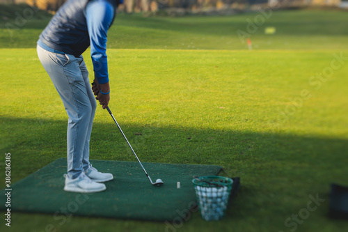 Group of golfers practicing and training golf swing on driving range practice, men playing on golf course, golf ball at golfing complex club resort photo