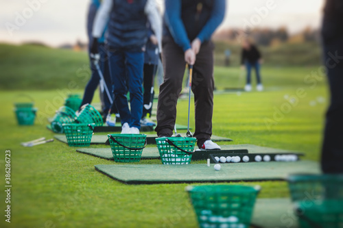 Bilde på lerret Group of golfers practicing and training golf swing on driving range practice, m
