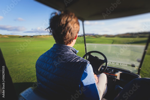 Golf electric cars riding on a golf course in the sunny day, golf carts drive with golfers in resort club