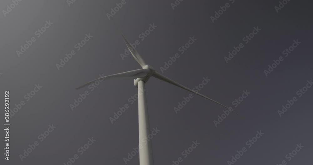 Wind turbine from bellow and in front, head spinning with blue sky background Wind turbine from bellow and in front, head spinning with blue sky background