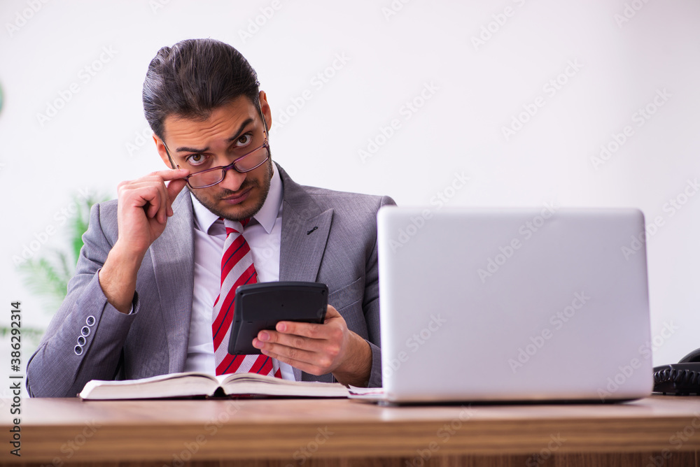 Young male bookkeeper working in the office Young male bookkeeper working in the office