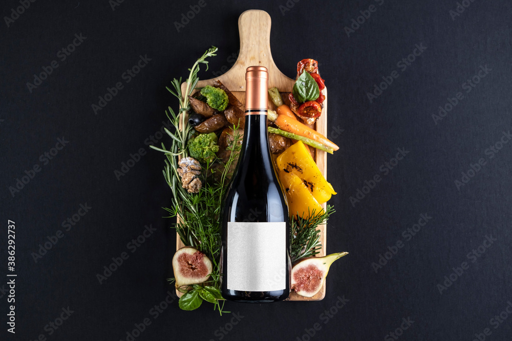 Bottle of wine lying down in black background with some food as