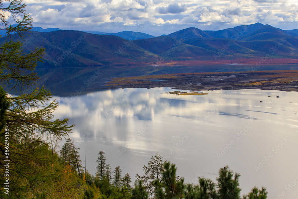 The nature of the Magadan region. Beautiful lake with smooth blue water against the background of high mountains in the Russian tundra