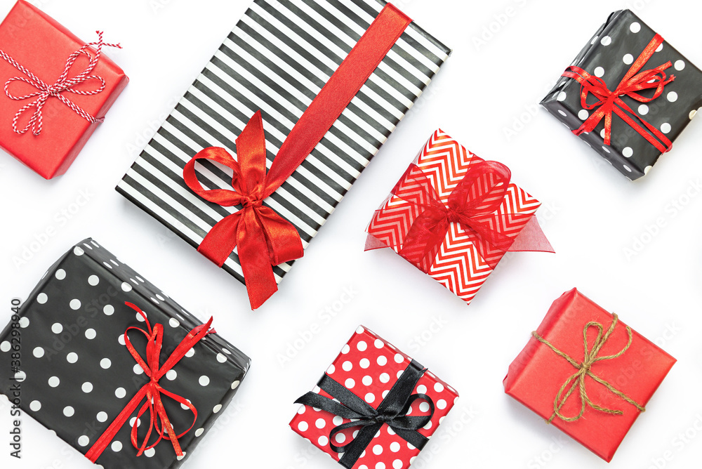 Top view of gift boxes wrapped in black and white striped, dotted and red paper over a white background. Various designs wrapped presents.
