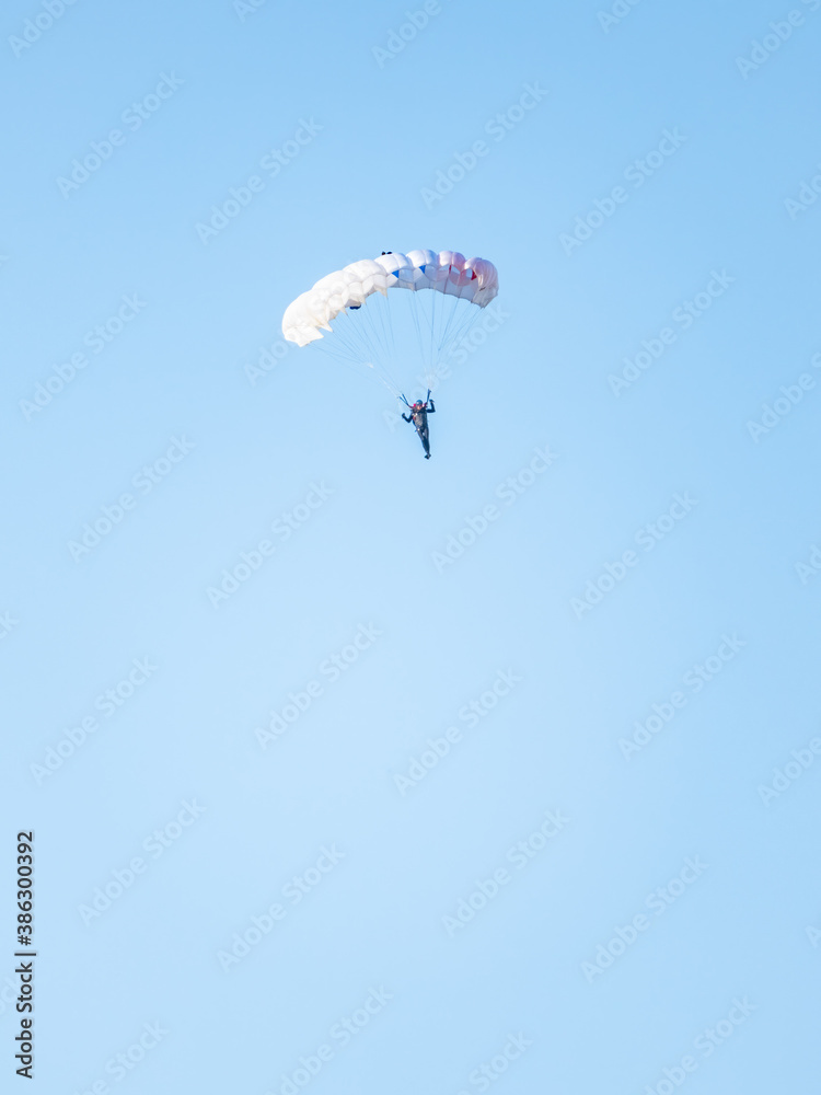 one parachutist floats slowly at low altitude on the background of clear sky one parachutist floats slowly at low altitude on the background of clear sky