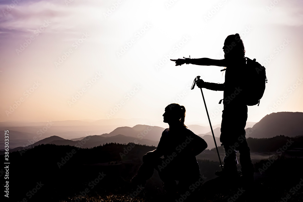 Obraz premium happy couple man and woman tourist at top of mountain at sunrise a hike in summer