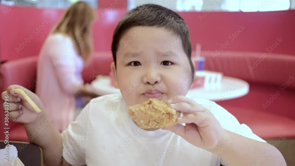 Happy little asian boy eating fried chicken chop in the restaurant. Happy little asian boy eating fried chicken chop in the restaurant.