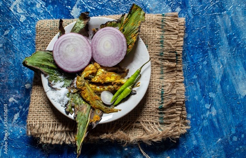 Cooked Indian Carplet Fish or Mourala Fish with Spices and Onion Slices in a Plate Isolated on Bluish Background photo