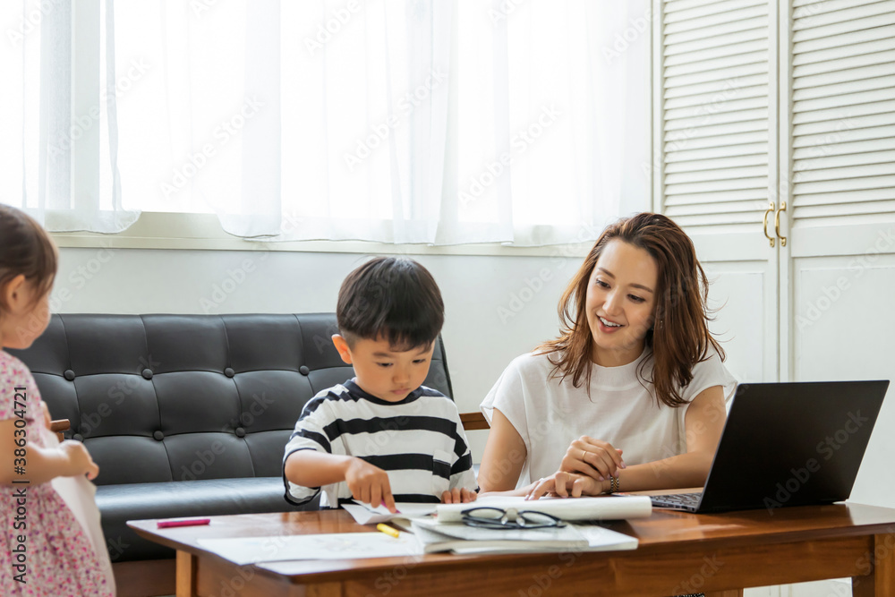 子供をあやしながらテレワークをする母親 子供をあやしながらテレワークをする母親