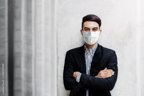 Portrait of Asian Young Businessman Wearing Surgical Mask and standing at the Wall, Smiling and Crossed Arms, Looking at camera