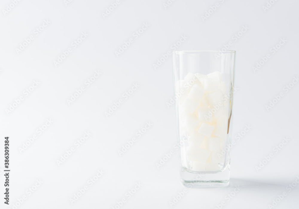 A glass full of white sugar cube sweet food ingredient, studio shot isolated on white background, health high blood risk of diabetes and calorie intake concept and unhealthy drink A glass full of white sugar cube sweet food ingredient, studio shot isolated on white background, health high blood risk of diabetes and calorie intake concept and unhealthy drink