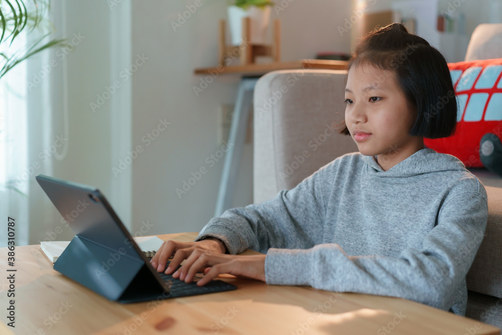 Asian woman using tablet while sitting in the living room at home Asian woman using tablet while sitting in the living room at home