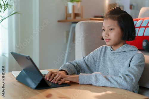 Asian woman using tablet while sitting in the living room at home