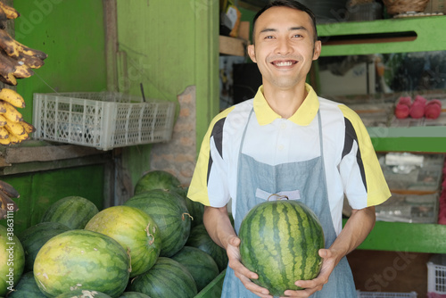 Shop waitress boy in apron carry watermelon at fruit stand  fresh fruit concept