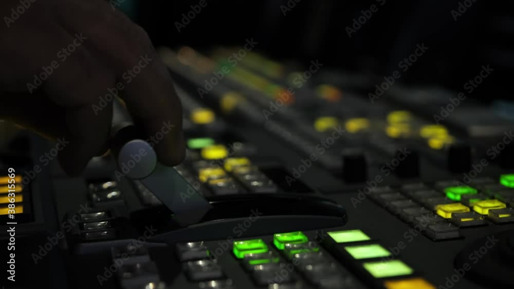Television director is moving handle on a control panel during tv filming in studio
