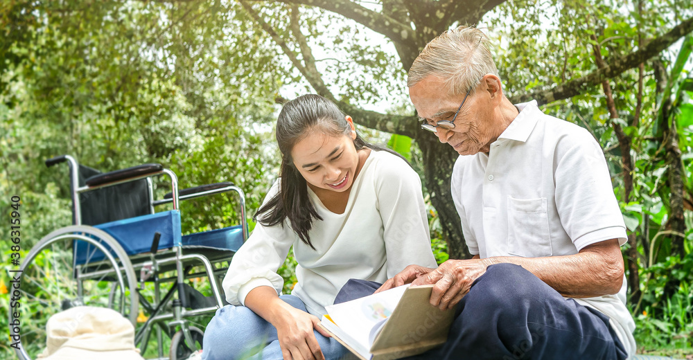 Happy disabled grandfather relaxing with granddaughter outdoor at the park. Family happy lifestyle. Happy disabled grandfather relaxing with granddaughter outdoor at the park. Family happy lifestyle.
