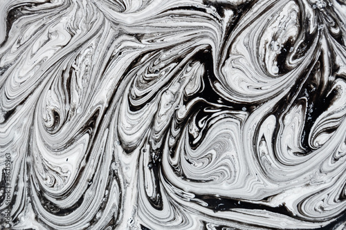 Mix of a white and black paint, closeup. Abstract background.