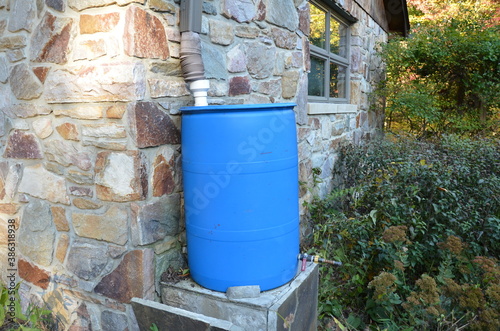 blue rain barrel with downspout and stone building
