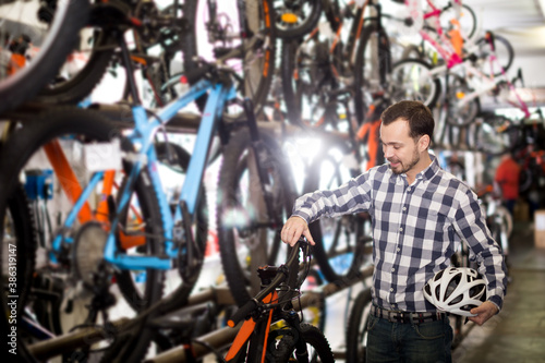 Man considers bicycle handlebar in store when choosing bike