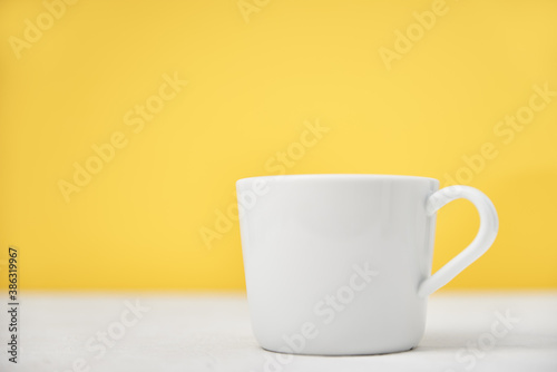 White cup on a yellow background with copy space