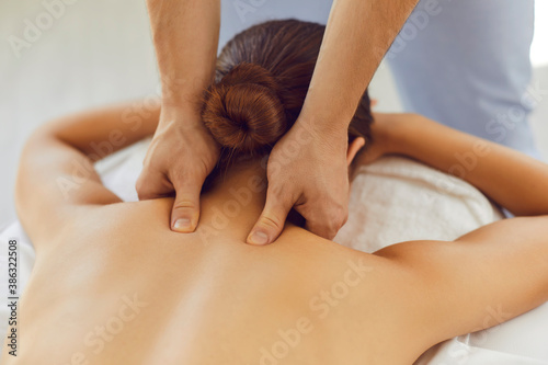Obraz na plátně Men's hands do a therapeutic neck massage for a girl lying on a massage couch in a massage spa