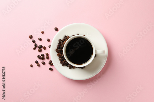Cup of coffee and beans on pink background