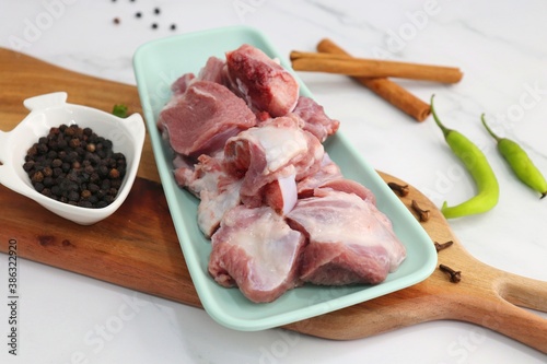 Fresh raw goat meat or mutton or lamb pieces. Preparation for Indian mutton curry. Spice at the background such as cinnamon sticks, red chili powder, black pepper & coriander. Copy space. photo