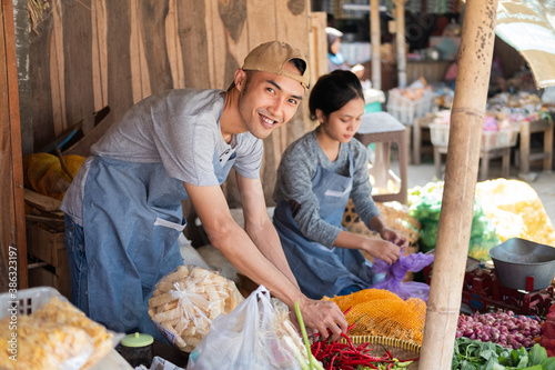 Tableau sur toile Asian greengrocer couple tidying up a vegetable display at a vegetable stall in