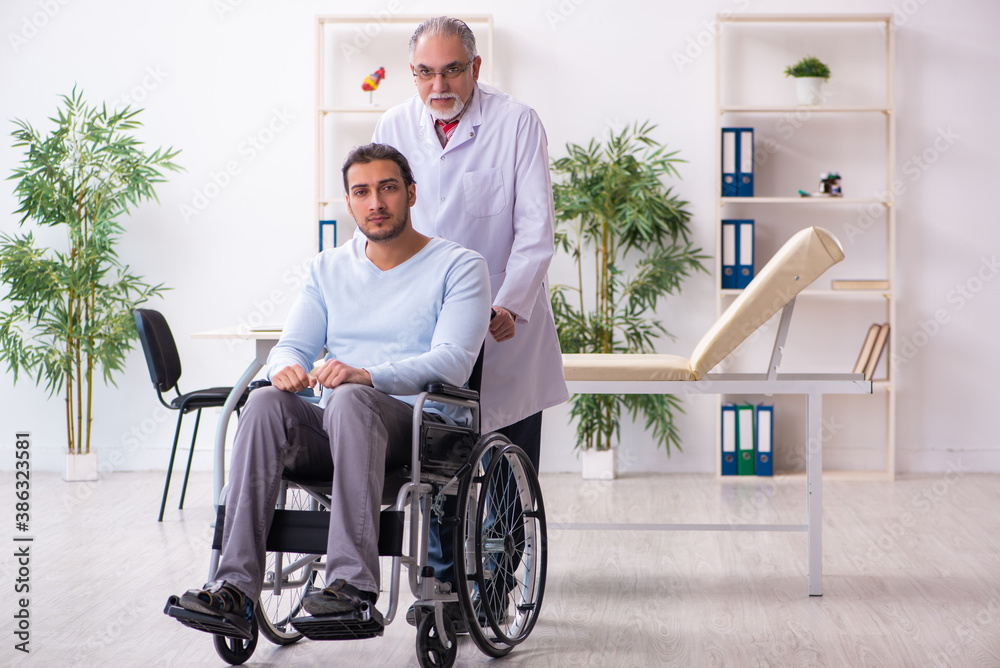 Young man in wheel-chair and old doctor traumatologist Young man in wheel-chair and old doctor traumatologist