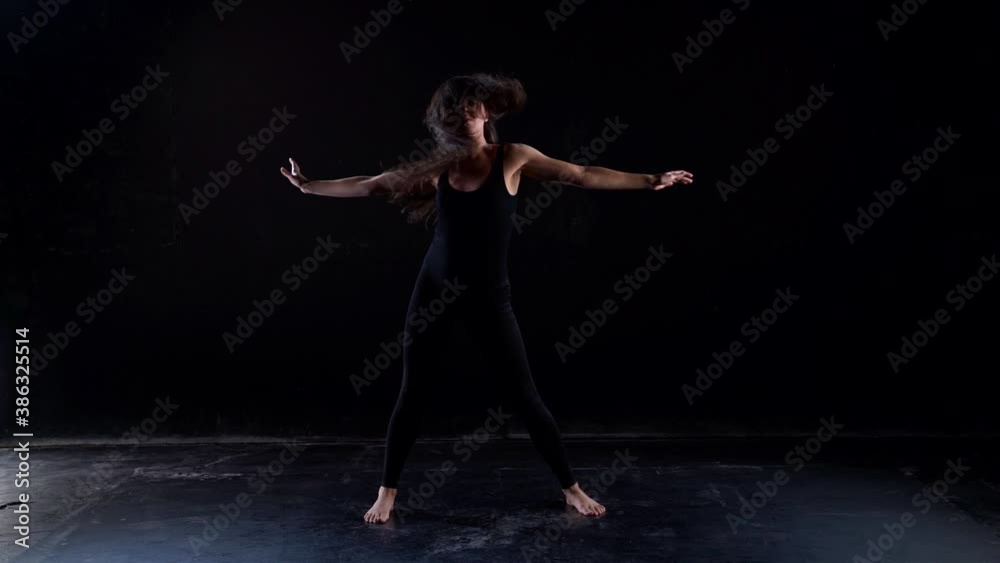 dancing gymnast woman in dark room, female figure is moving on black background dancing gymnast woman in dark room, female figure is moving on black background