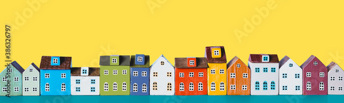 Row of wooden miniature colorful retro houses on a yellow background photo