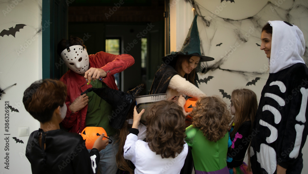 Hosts giving candies to a group of trick-or-treating kids during Halloween Hosts giving candies to a group of trick-or-treating kids during Halloween