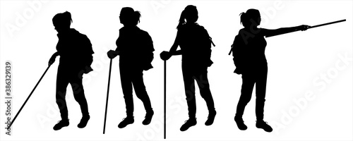 Girls with walking sticks in hands. Tourists with backpacks behind their backs in the hike. Women pick a road, show a direction with a walking stick. Silhouettes are isolated on a white background.