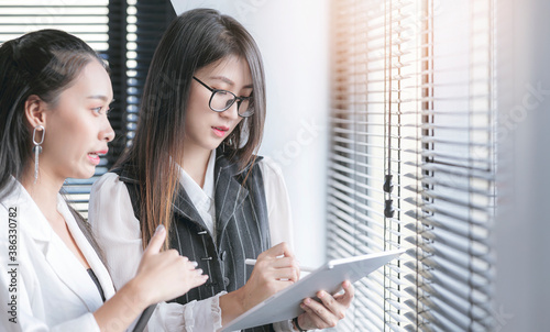 Two businesswoman using tablet and discussing about business while standing at office room.