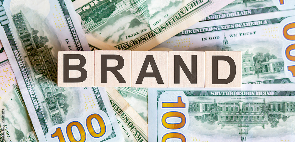 Concept words BRAND on wooden blocks on a beautiful background from dollar bills. Concept words BRAND on wooden blocks on a beautiful background from dollar bills.