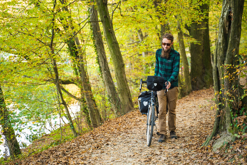 Attractive hipster man with bicycle at a public park during autumn.