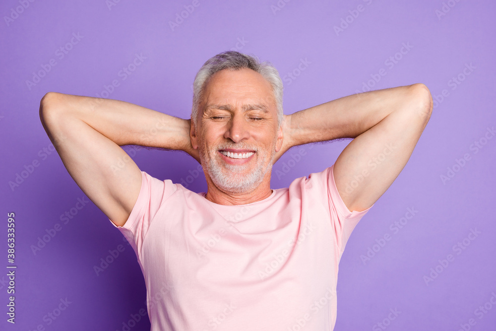 Photo of retired old man arms behind head closed eyes beaming smile wear pink t-shirt isolated purple color background Photo of retired old man arms behind head closed eyes beaming smile wear pink t-shirt isolated purple color background