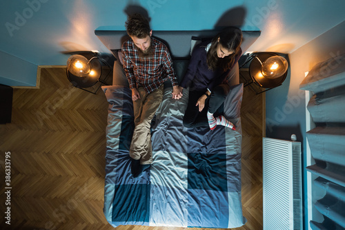 Image from above of young couple watching tv on the bed together.