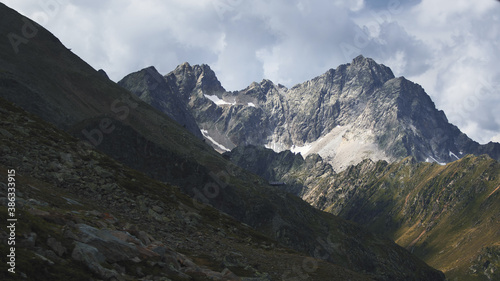 Aerial shot of the high mountains of the Austrian Alps in Kuhtai during summer season. The sunshine illuminates the beautiful landscape.