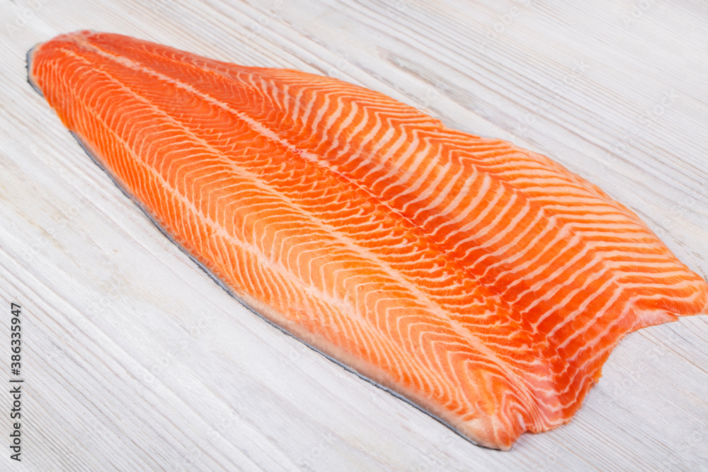 Half raw salmon fillet on wooden table Half raw salmon fillet on wooden table