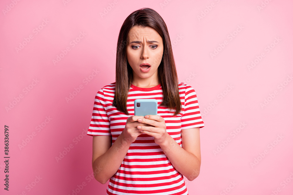 Photo of impressed sad young lady look telephone open mouth wear casual t-shirt isolated over pink background Photo of impressed sad young lady look telephone open mouth wear casual t-shirt isolated over pink background
