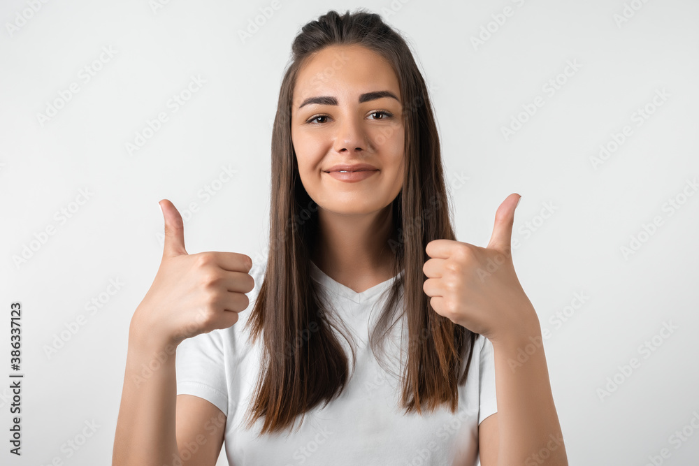 Cheerful girl showing thumbs up with both hands. Human emotions facial expression concept. Studio shot, white background Cheerful girl showing thumbs up with both hands. Human emotions facial expression concept. Studio shot, white background