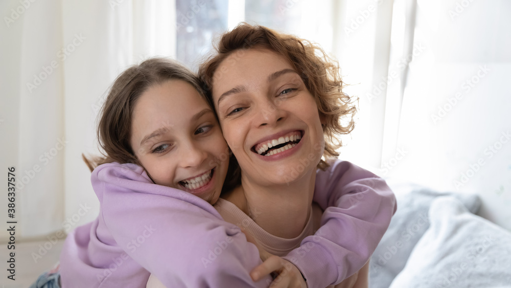 Wide narrow panoramic view self-portrait picture of smiling Caucasian mom and teen daughter hugging cuddling at home. Happy mother and teenager girl child embrace show love and care in relationship. Wide narrow panoramic view self-portrait picture of smiling Caucasian mom and teen daughter hugging cuddling at home. Happy mother and teenager girl child embrace show love and care in relationship.