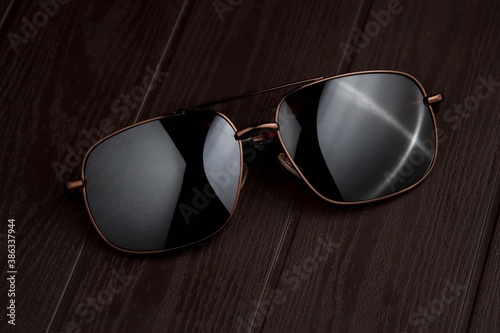 Sunglass on brown textured wood table with dark background 