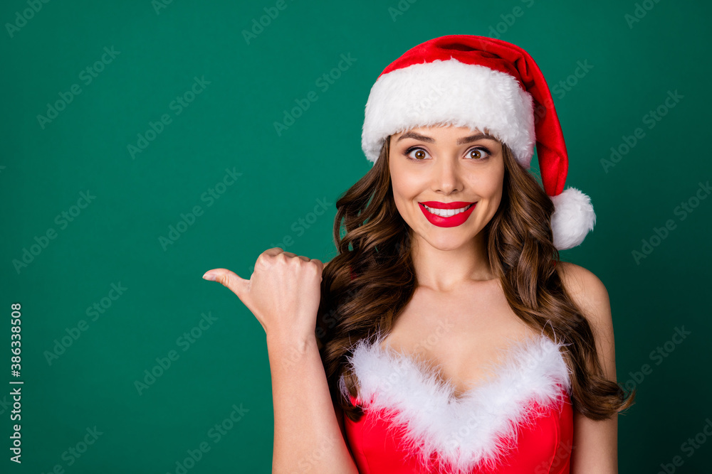 Clsoeup photo of attractive charming lady good mood excited emotion direct thumb finger side empty space novelty wear red snow girl fluffy dress santa cap isolated green color background