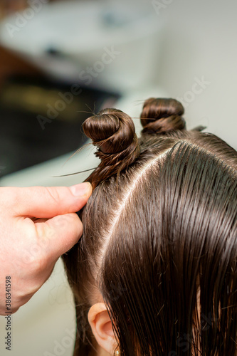Young woman receives process of hairstyle by hairdresser at beauty hair salon