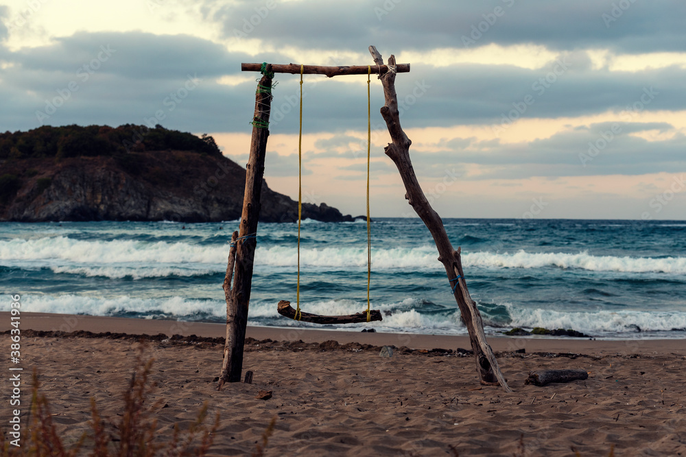 Wooden swing on an empty beach during the romantic sundown Selective focus Wooden swing on an empty beach during the romantic sundown Selective focus